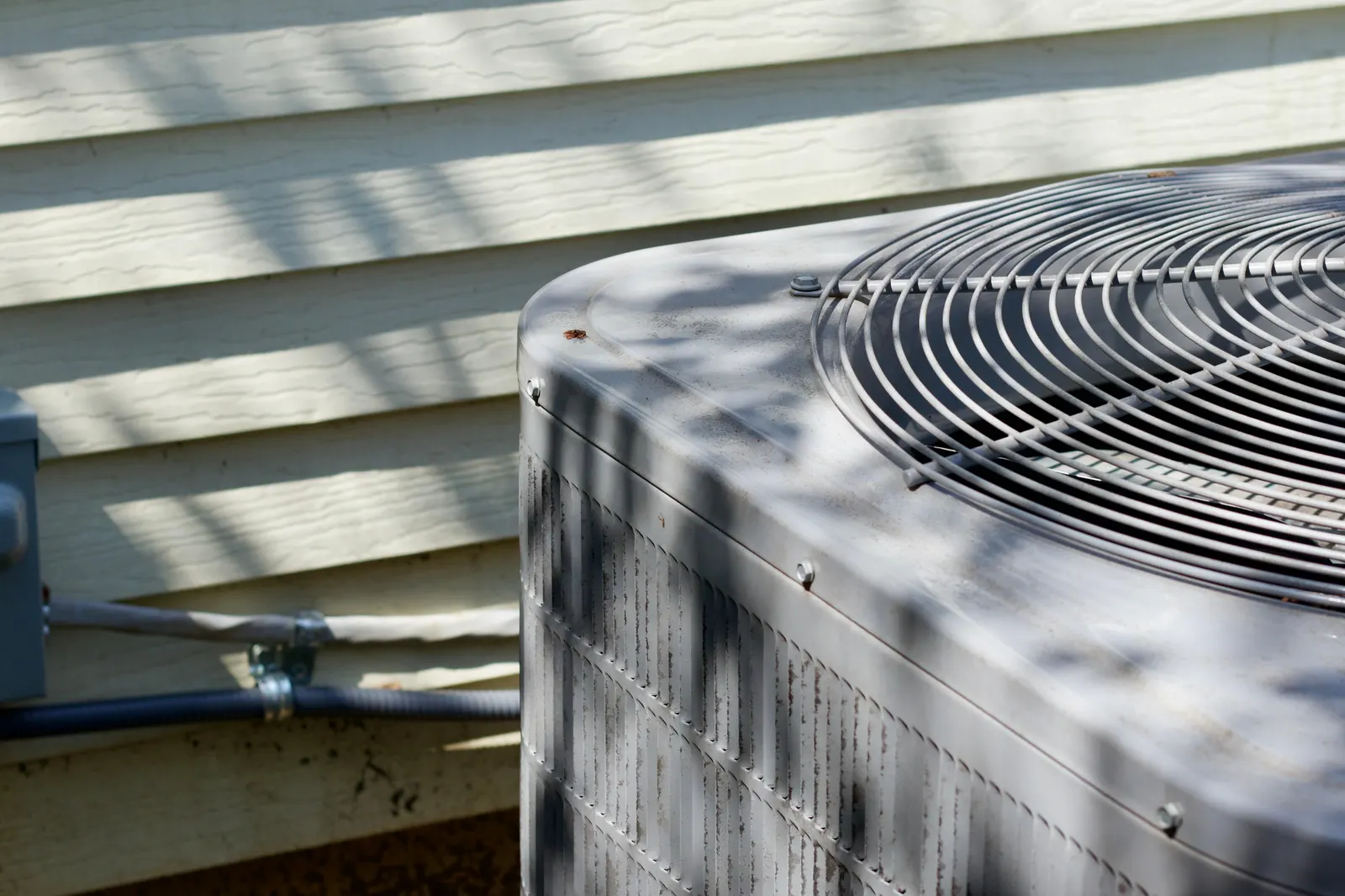 Outdoor AC condenser unit beside a house before repair