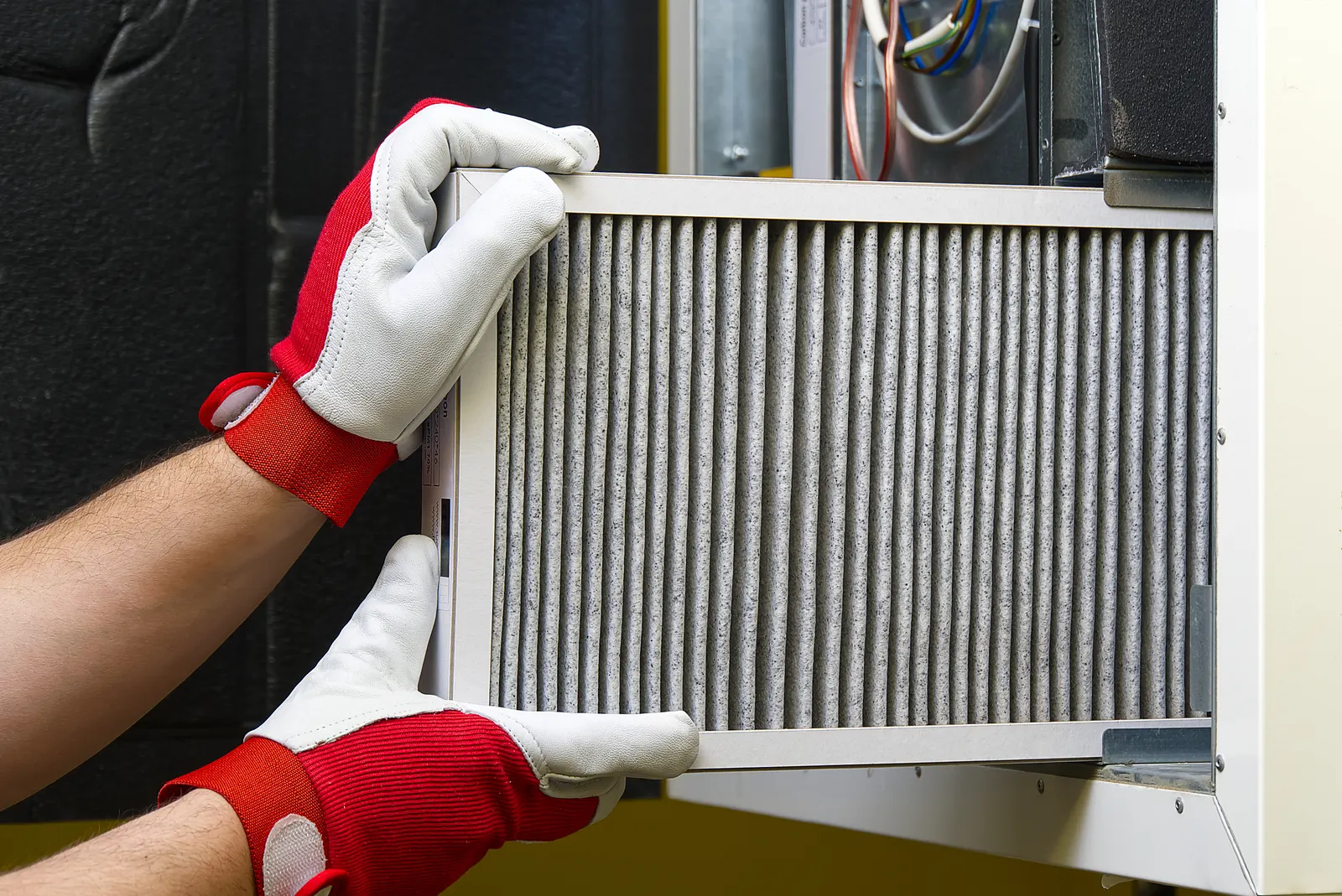 Hands replacing a furnace filter during a maintenance visit
