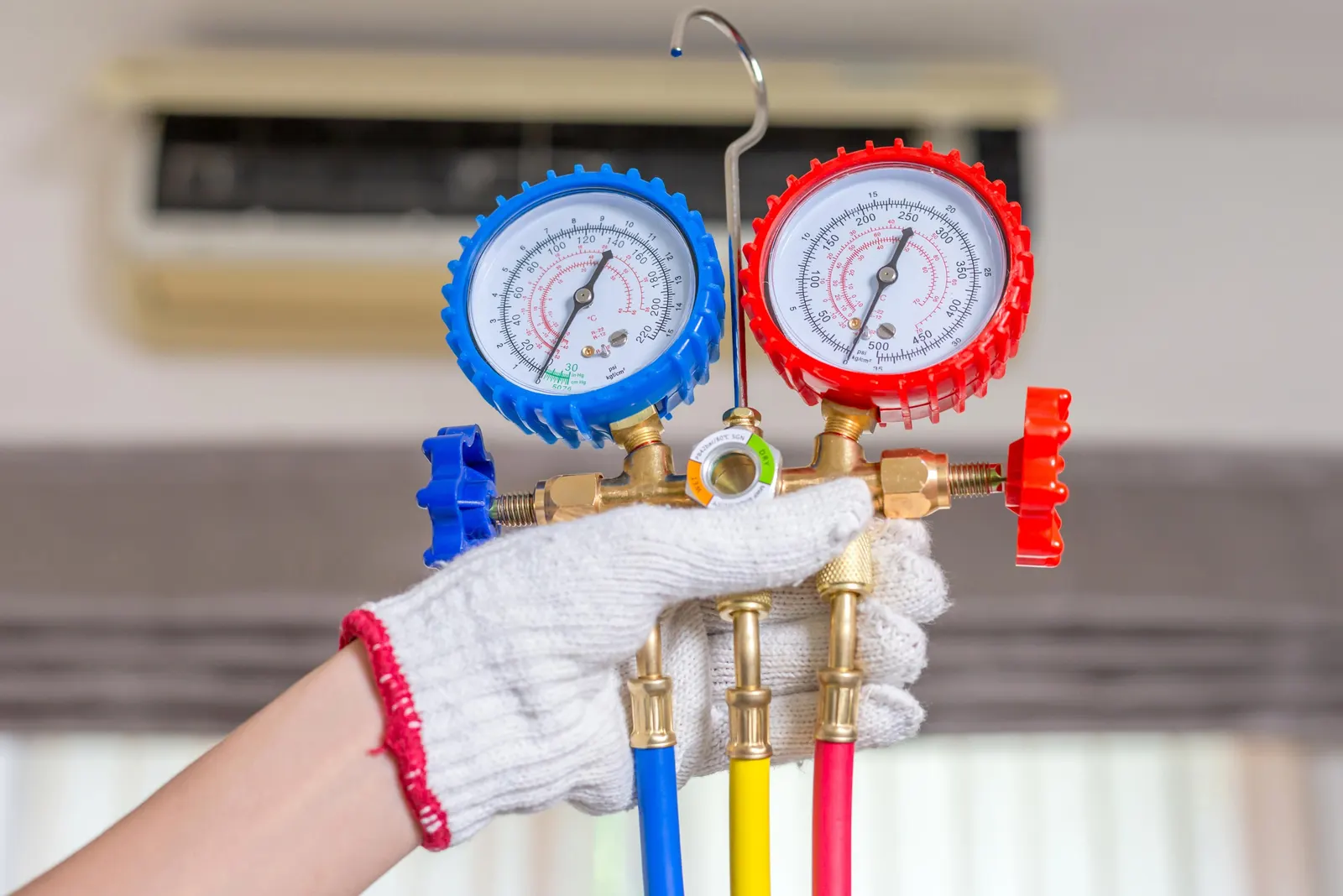 Hands checking HVAC gauges during a repair visit