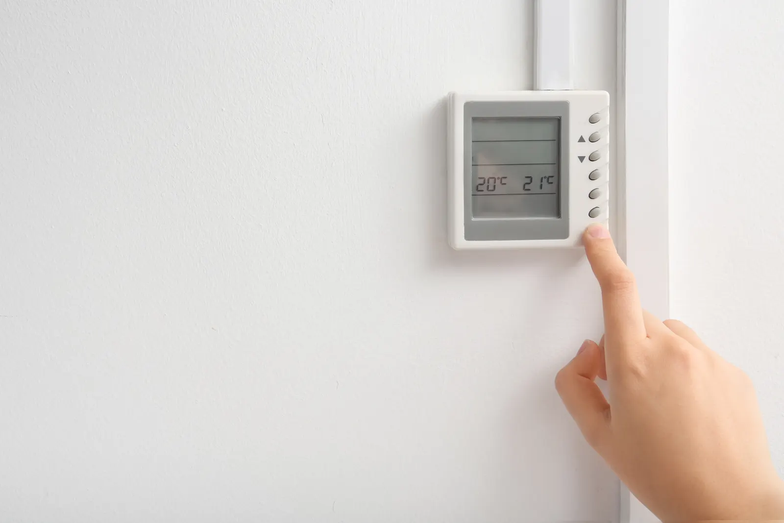 Hand adjusting a wall thermostat